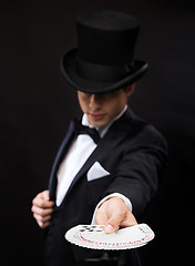 Image showing magician in hat showing trick with playing cards