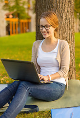 Image showing smiling teenager in eyeglasses with laptop