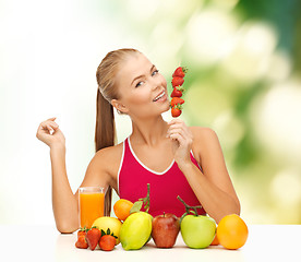 Image showing smiling woman with organic food eating strawberry