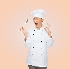 Image showing smiling female chef with fork and tomato