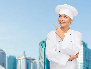 Image showing smiling female chef pointing finger to sonething