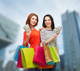 Image showing smiling teenage girls with shopping bags and money