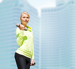 Image showing sporty woman with light dumbbells outdoors