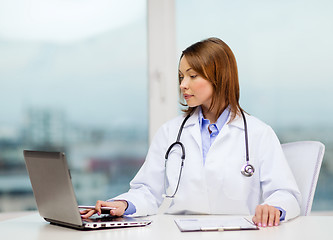 Image showing busy doctor with laptop computer and clipboard