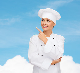 Image showing smiling female chef pointing finger to sonething