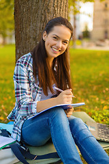 Image showing smiling teenager writing in notebook