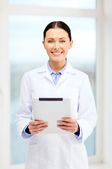 Image showing smiling young doctor with tablet pc in cabinet