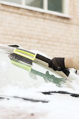 Image showing closeup of man cleaning snow from car