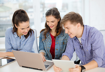 Image showing three smiling students with laptop and tablet pc