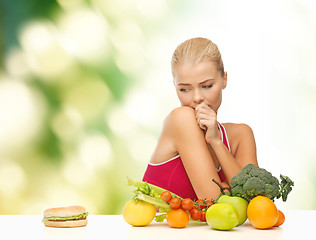 Image showing doubting woman with fruits and hamburger