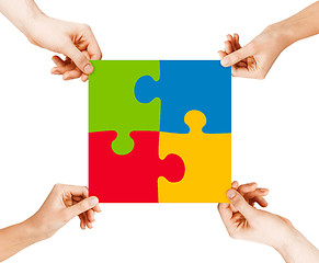 Image showing four hands connecting puzzle pieces