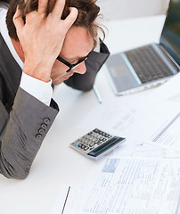 Image showing businessman with papres, laptop and calculator