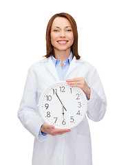 Image showing smiling female doctor with wall clock