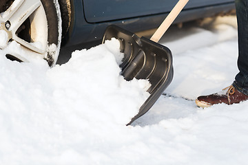 Image showing closeup of man digging up stuck in snow car