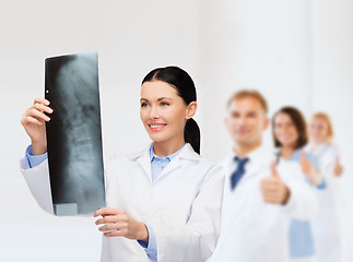 Image showing smiling female doctor looking at x-ray