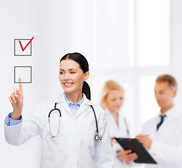 Image showing smiling female doctor pointing checkbox