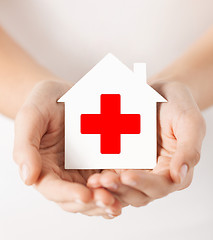 Image showing hands holding paper house with red cross