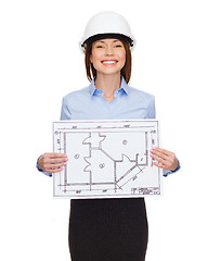 Image showing smiling businesswoman in helmet showing blueprint