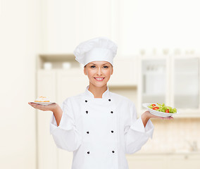 Image showing smiling female chef with salad and cake on plates