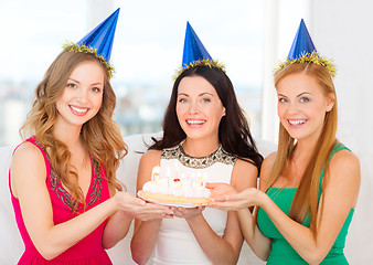 Image showing three women wearing hats holding cake with candles