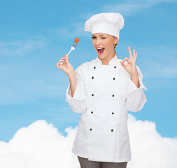 Image showing smiling female chef with fork and tomato