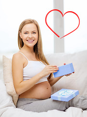 Image showing smiling pregnant woman opening gift box