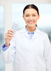 Image showing smiling young doctor in cabinet with pills