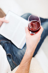 Image showing male hand holdind book and glass of red wine