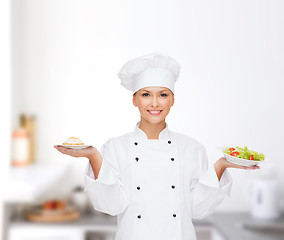 Image showing smiling female chef with salad and cake on plates