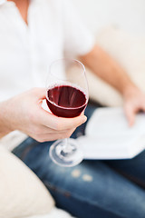 Image showing male hand holdind book and glass of red wine