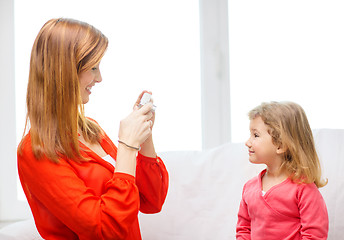 Image showing smiling mother taking picture of daughter