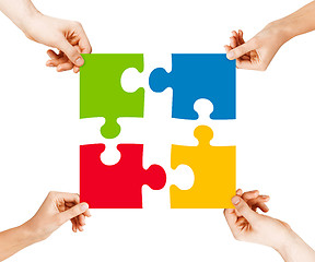 Image showing four hands connecting puzzle pieces