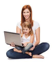 Image showing happy mother with adorable little girl and laptop