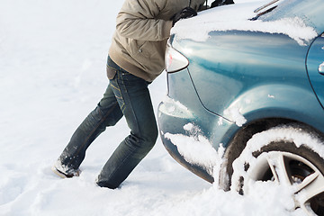 Image showing closeup of man pushing car stuck in snow