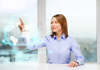Image showing smiling woman pointing to earth hologram