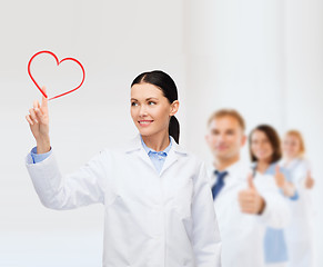 Image showing smiling female doctor pointing to heart