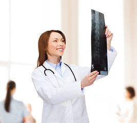 Image showing smiling female doctor looking at x-ray