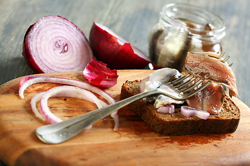 Image showing Fork with anchovies, rye bread and red onion.