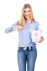Image showing Woman pointing to a piggy bank