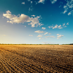 Image showing black field after harvesting and blue cloudy sky