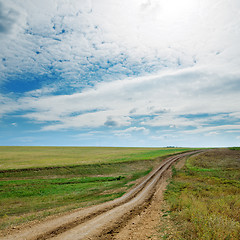 Image showing rural road in green fields and cloudy sky