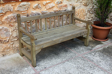 Image showing old wooden bench near stone wall