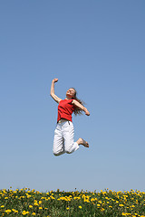 Image showing Smiling happy girl jumps in flowering field