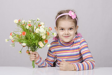 Image showing Girl with a bouquet of flowers sitting at table