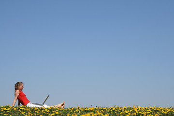 Image showing Girl relaxing with laptop in flowering field