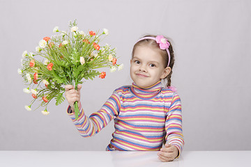 Image showing Girl with a bouquet of flowers sitting at table