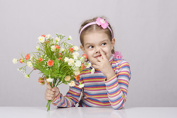 Image showing Girl with a bouquet of flowers sitting at table