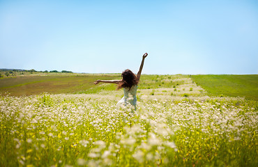 Image showing Girl lifting her hands up in the air runs across the field