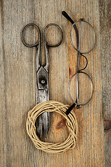 Image showing old scissors, glasses and hank of packthread over wooden texture