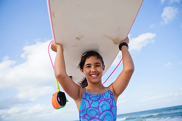 Image showing Happy young girl holding surfboard on head